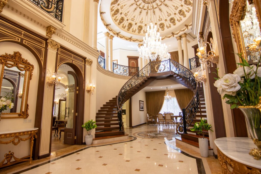 Art Deco üslubunda lüks interyer – bəzəkli pilləkən, qızılı detallar və kristal çilçıraq ilə zəngin dizayn.